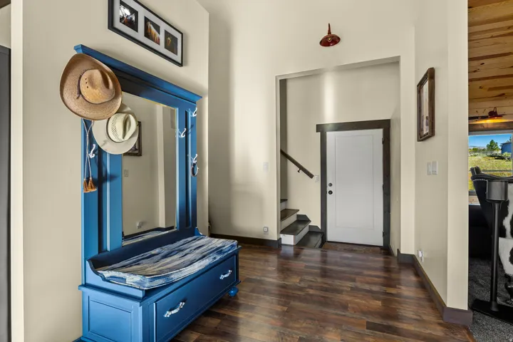 Entryway featuring wood-finish flooring, a white paneled door with dark trim, and a staircase with dark treads and a wood handrail