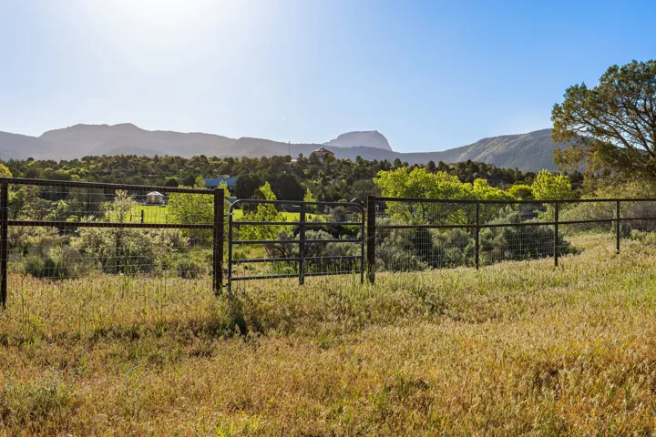 Expansive open acreage with a perimeter wire fence and gate