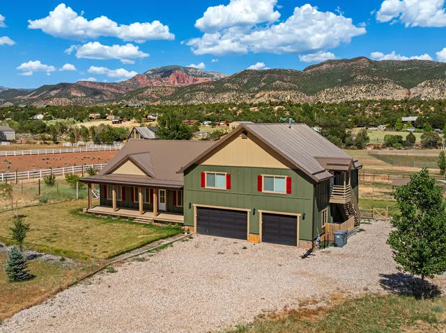 Two-story property featuring a covered front porch, dark green siding, and a metal roof