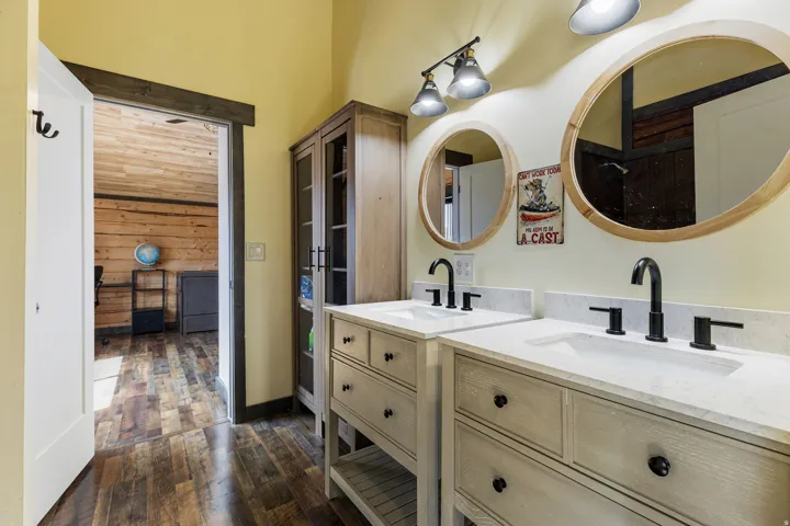 Bathroom featuring a double vanity with white countertops, matte black fixtures, and circular wood-framed mirrors