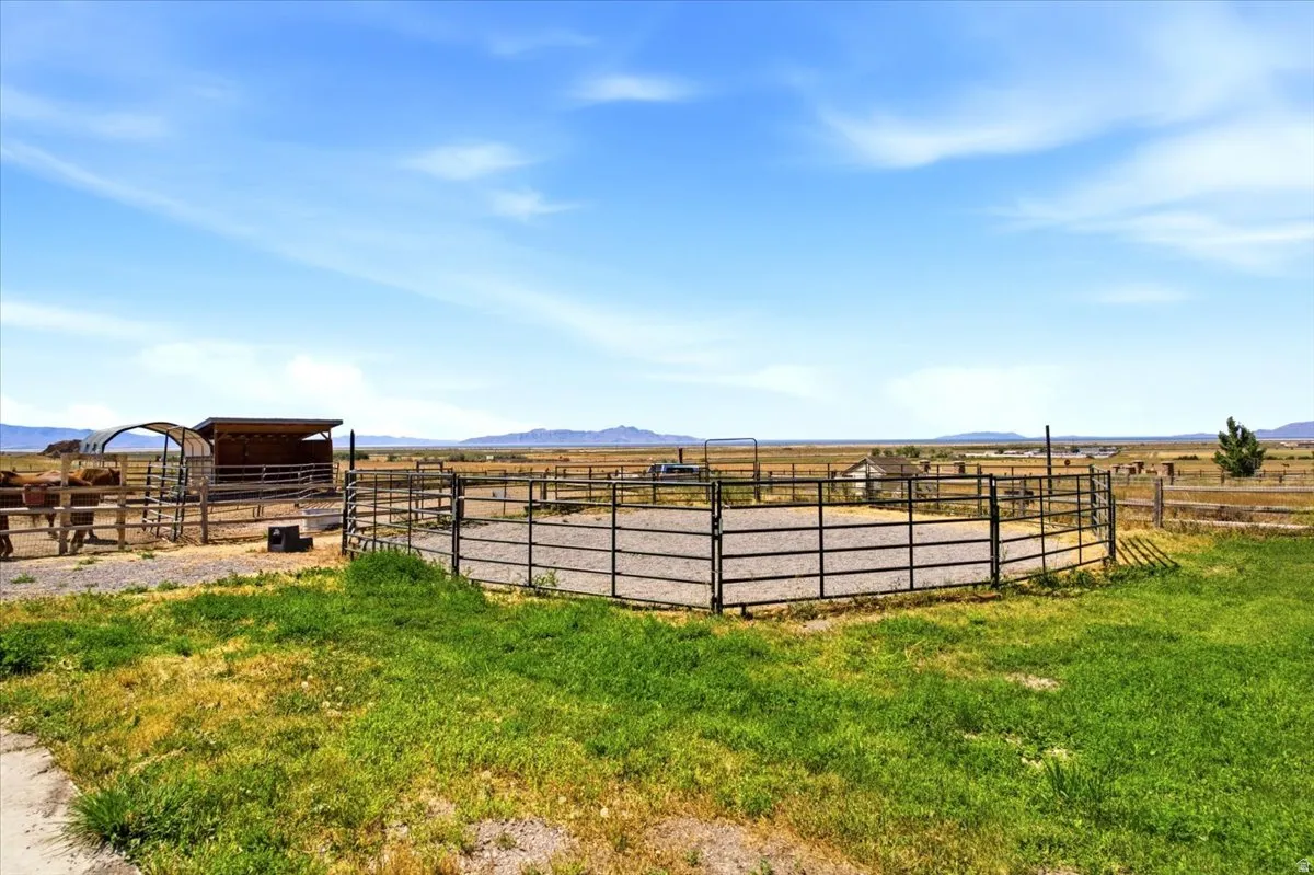 Expansive outdoor property featuring a round pen with a metal fence, a shaded animal shelter, and additional fenced enclosures