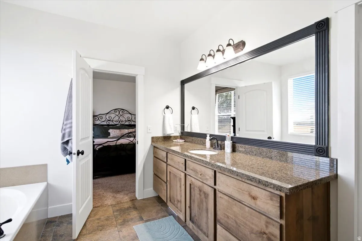 Bathroom vanity featuring a granite countertop, undermount sink, and wood-finish cabinetry