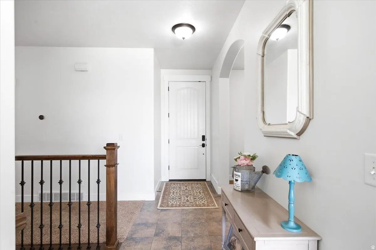 Front entry featuring tile flooring, a white paneled door, and an arched doorway
