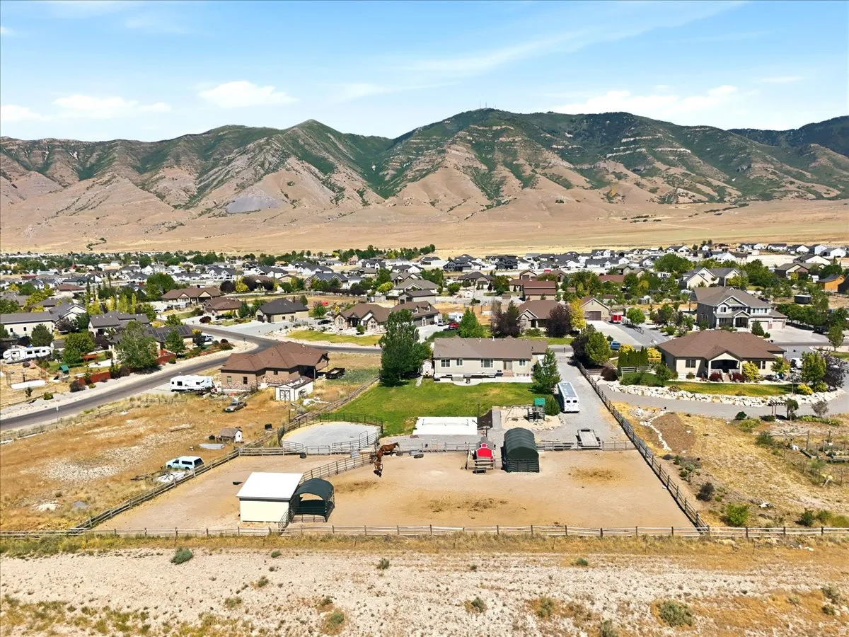 Expansive property featuring a fenced paddock, round pen, and two shelters, set against a backdrop of distant mountains