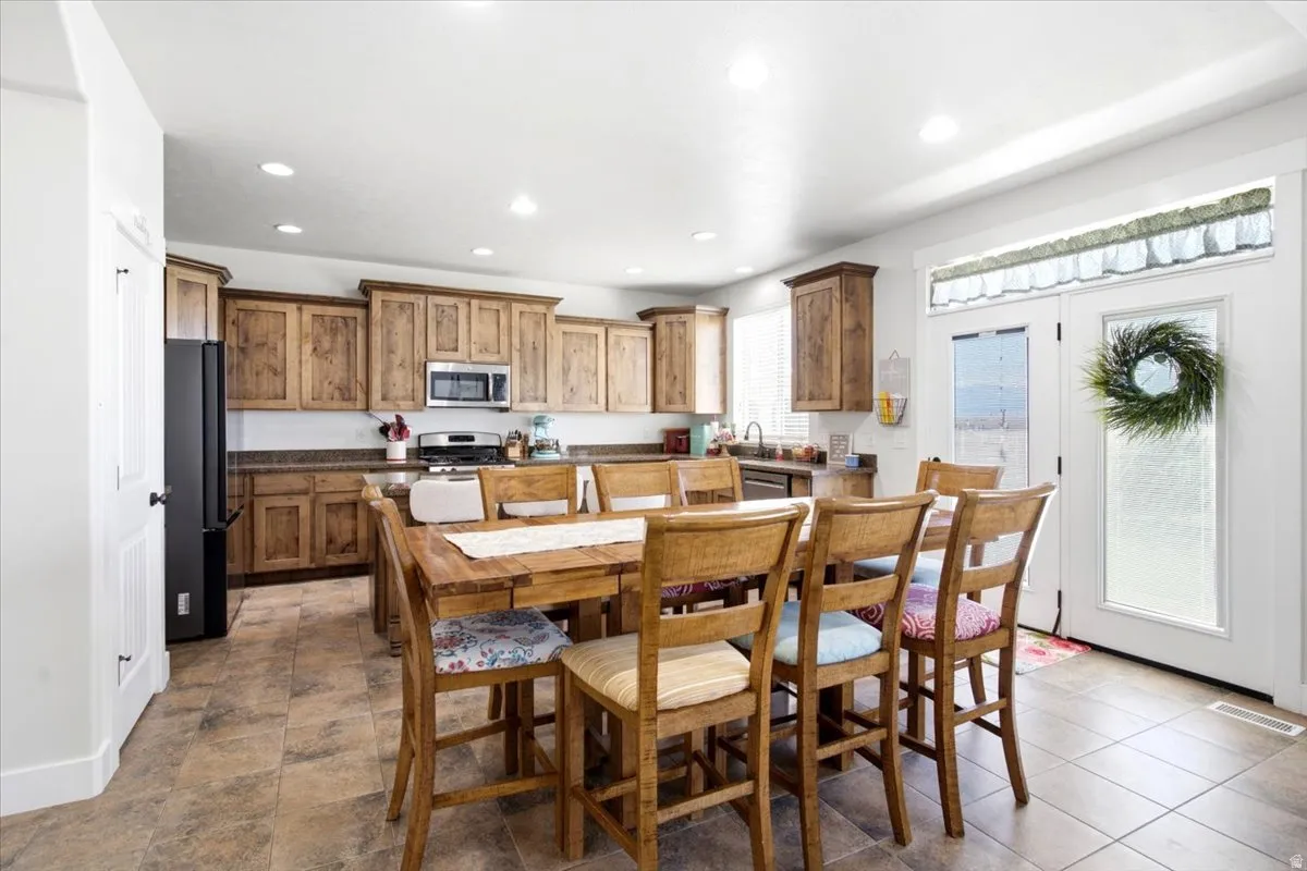 Spacious kitchen featuring wood cabinetry, stone countertops, stainless steel appliances, and tile flooring
