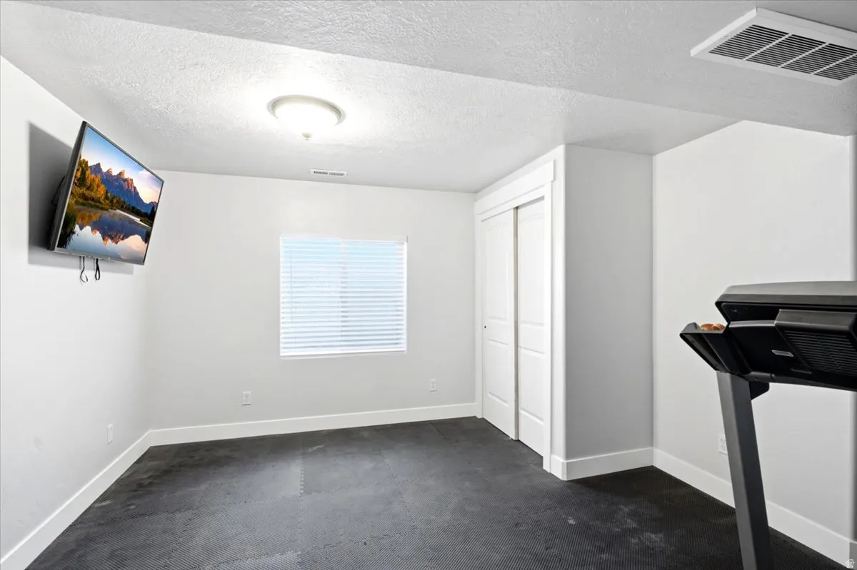 Flexible room featuring dark resilient flooring, a single window with blinds, and white bi-fold closet doors
