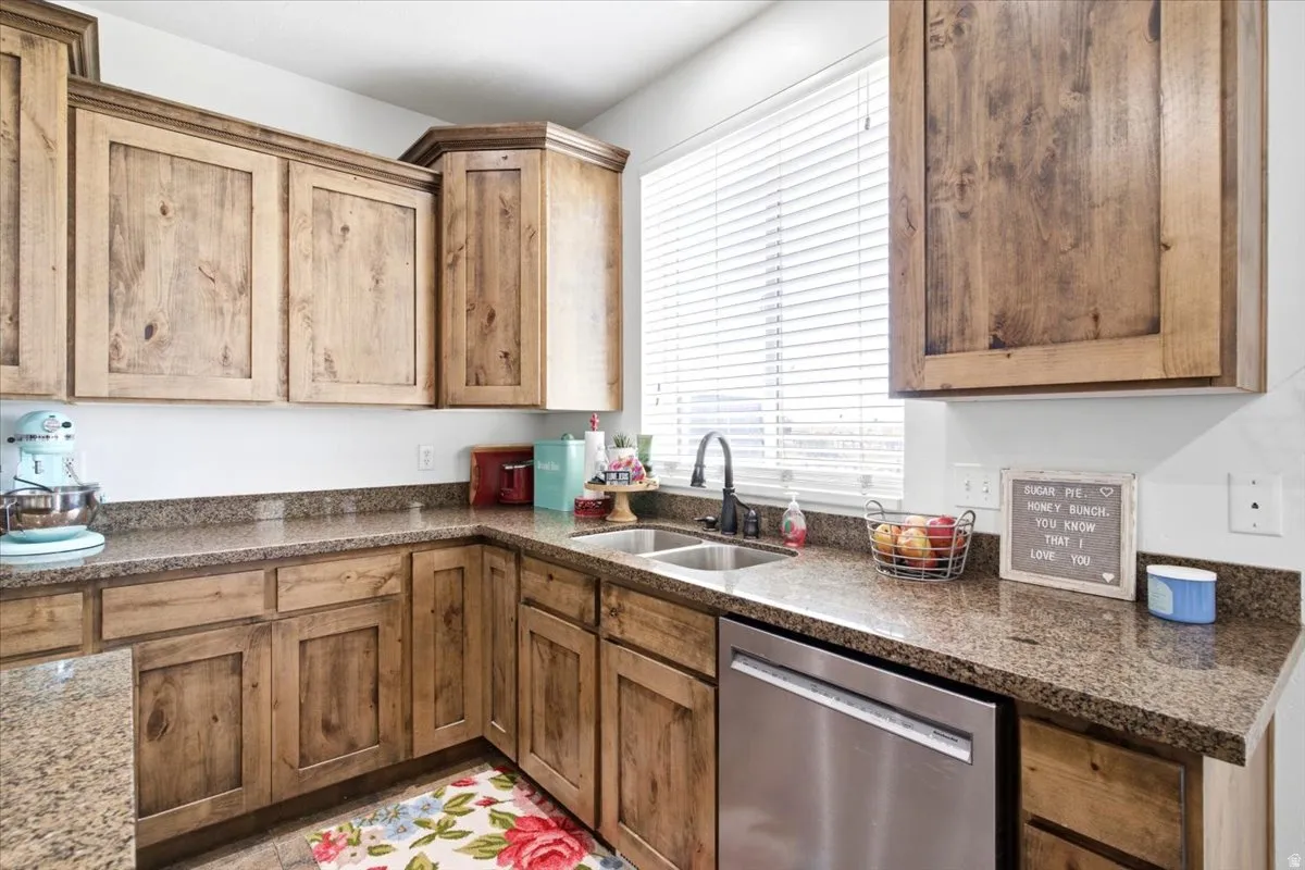 Kitchen featuring wood-finish cabinetry, granite countertops, and stainless steel dishwasher