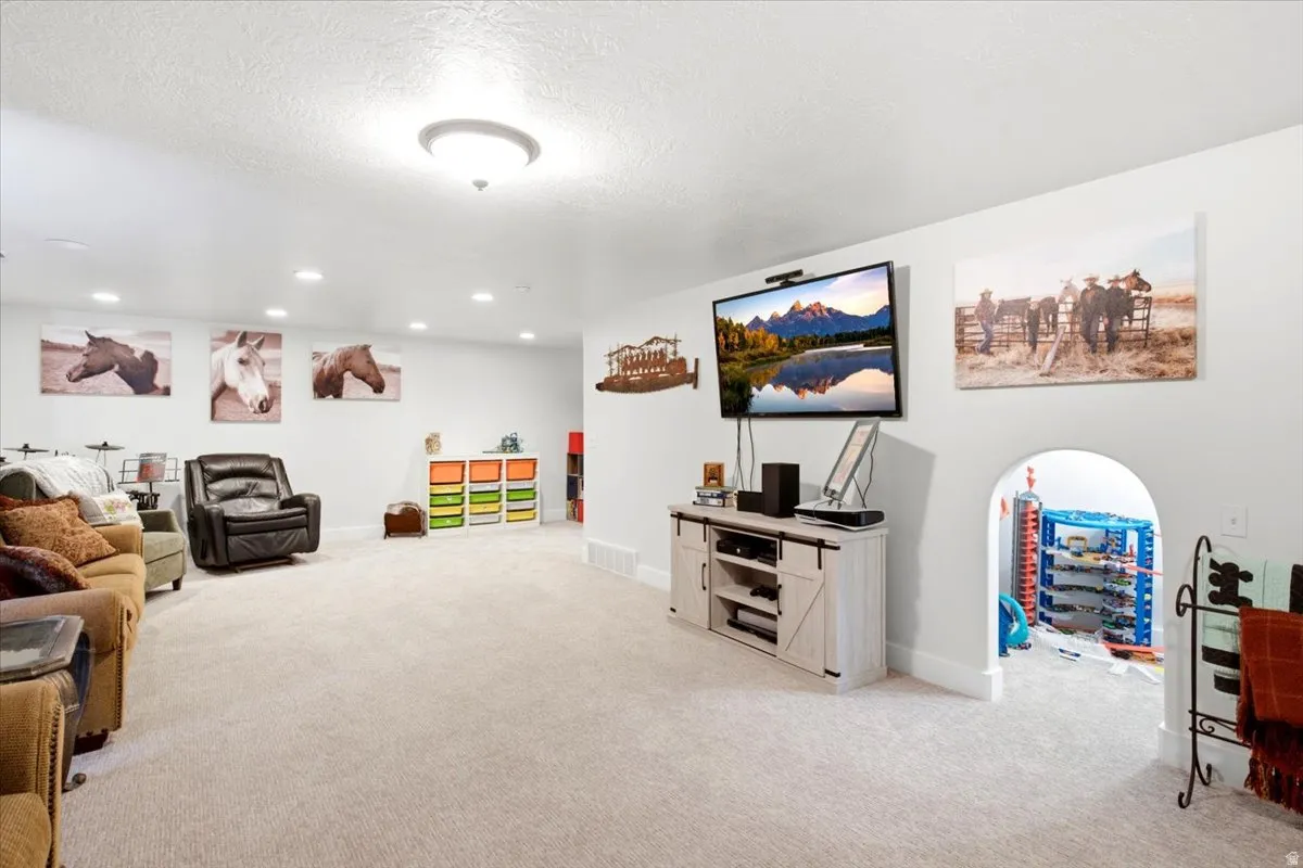 Spacious room featuring light-colored carpeting, white walls, recessed lighting, and a contemporary ceiling light fixture
