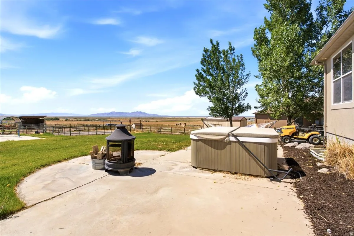 Concrete patio with a fire pit, hot tub, and expansive natural landscape