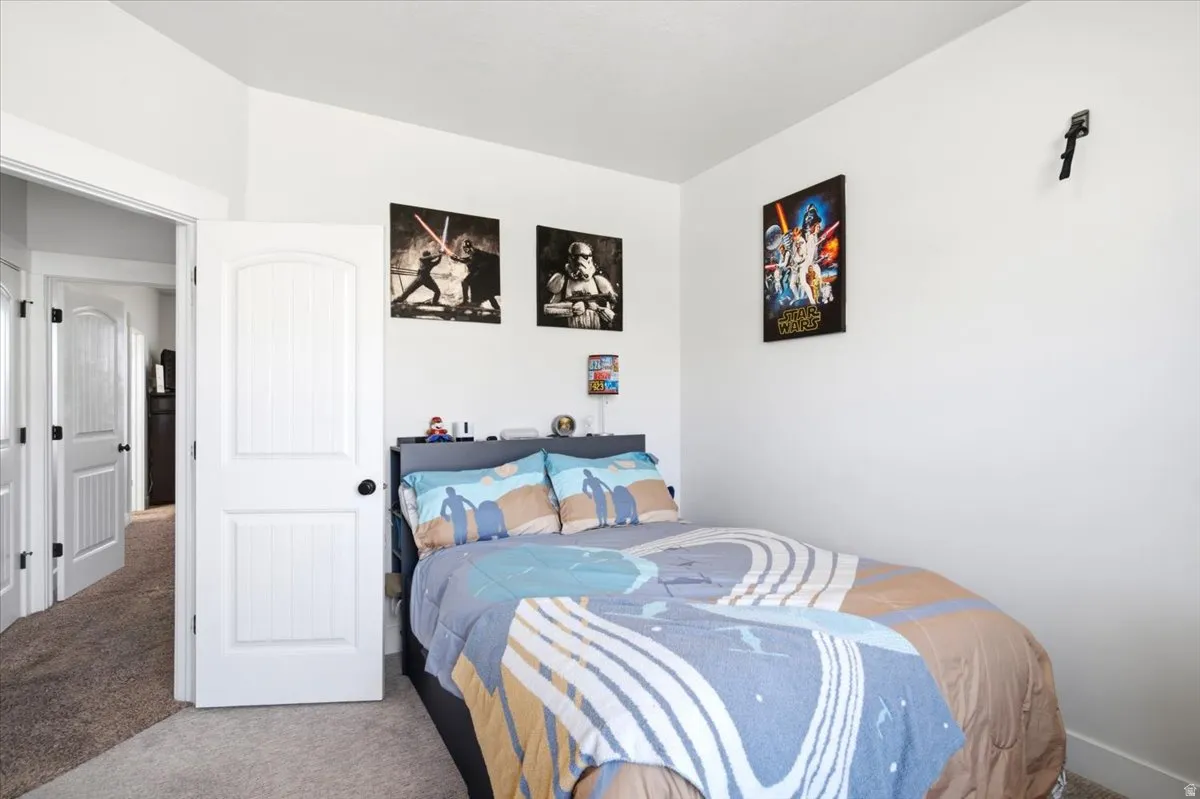 Carpeted room with white walls, white doors featuring black hardware, and a built-in headboard storage unit