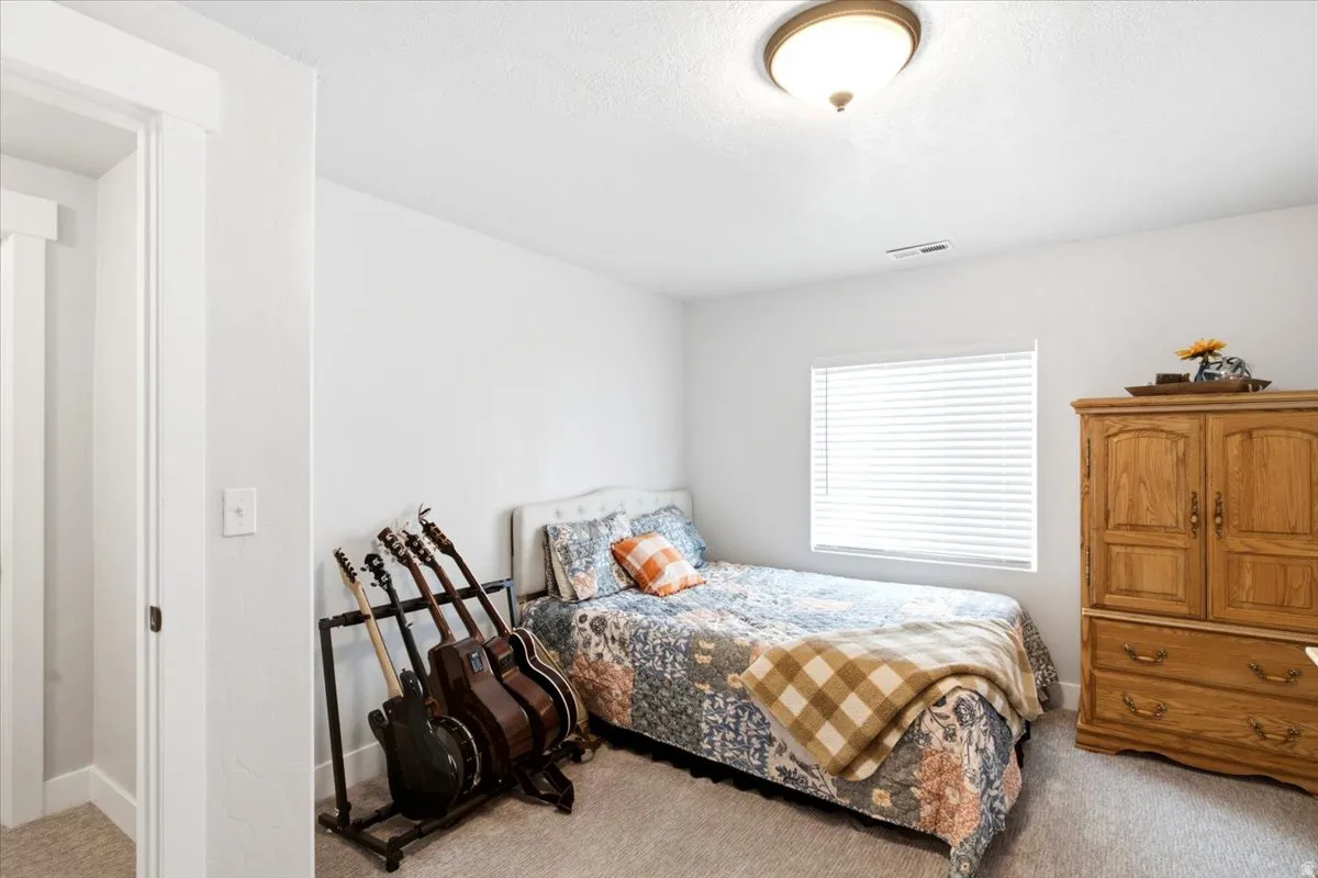 Bedroom featuring light gray carpet, white walls, and a single window with horizontal blinds