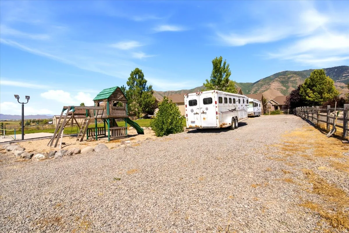 Expansive gravel driveway with a wood play structure featuring a slide and rock accents