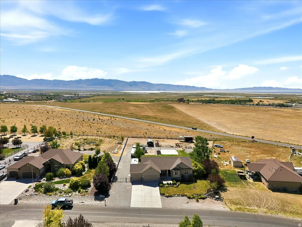 Aerial perspective showcasing a single-story residence with an attached garage, surrounded by mature landscaping and a paved driveway