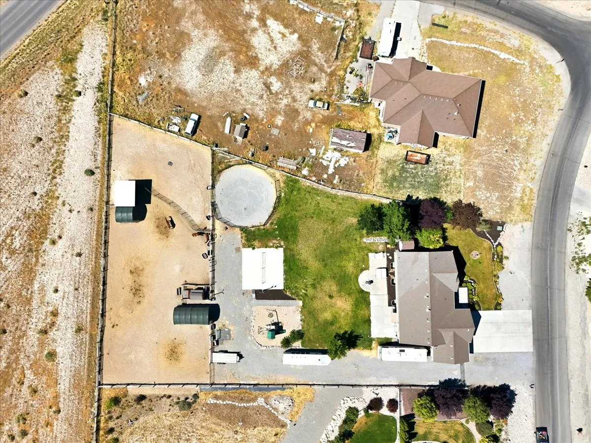 Expansive property featuring two residential structures, an equestrian round pen, multiple outbuildings, and a paved driveway