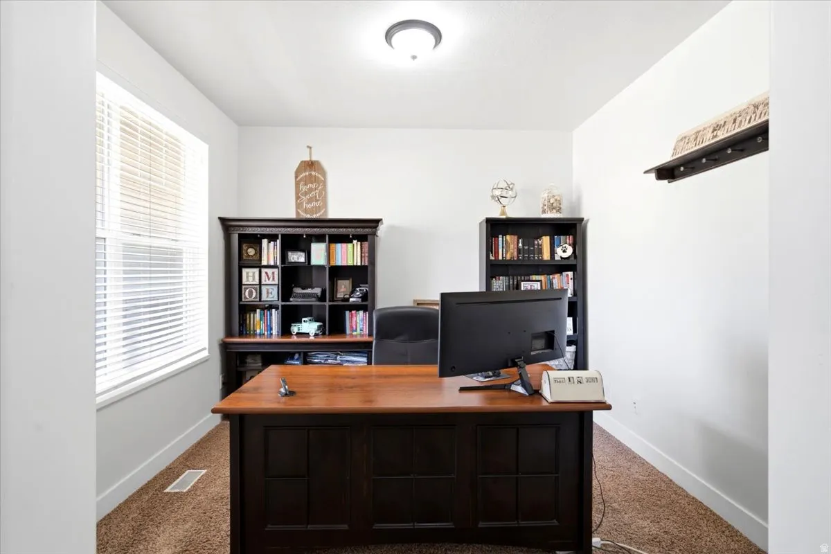 Dedicated room featuring a large window with horizontal blinds, built-in recessed shelving, a wood-finish desk, and overhead lighting