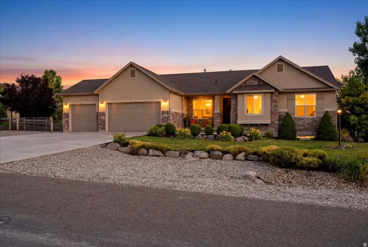 Ranch-style residence featuring a combination of stucco and stone veneer siding, a three-car garage, and a concrete driveway