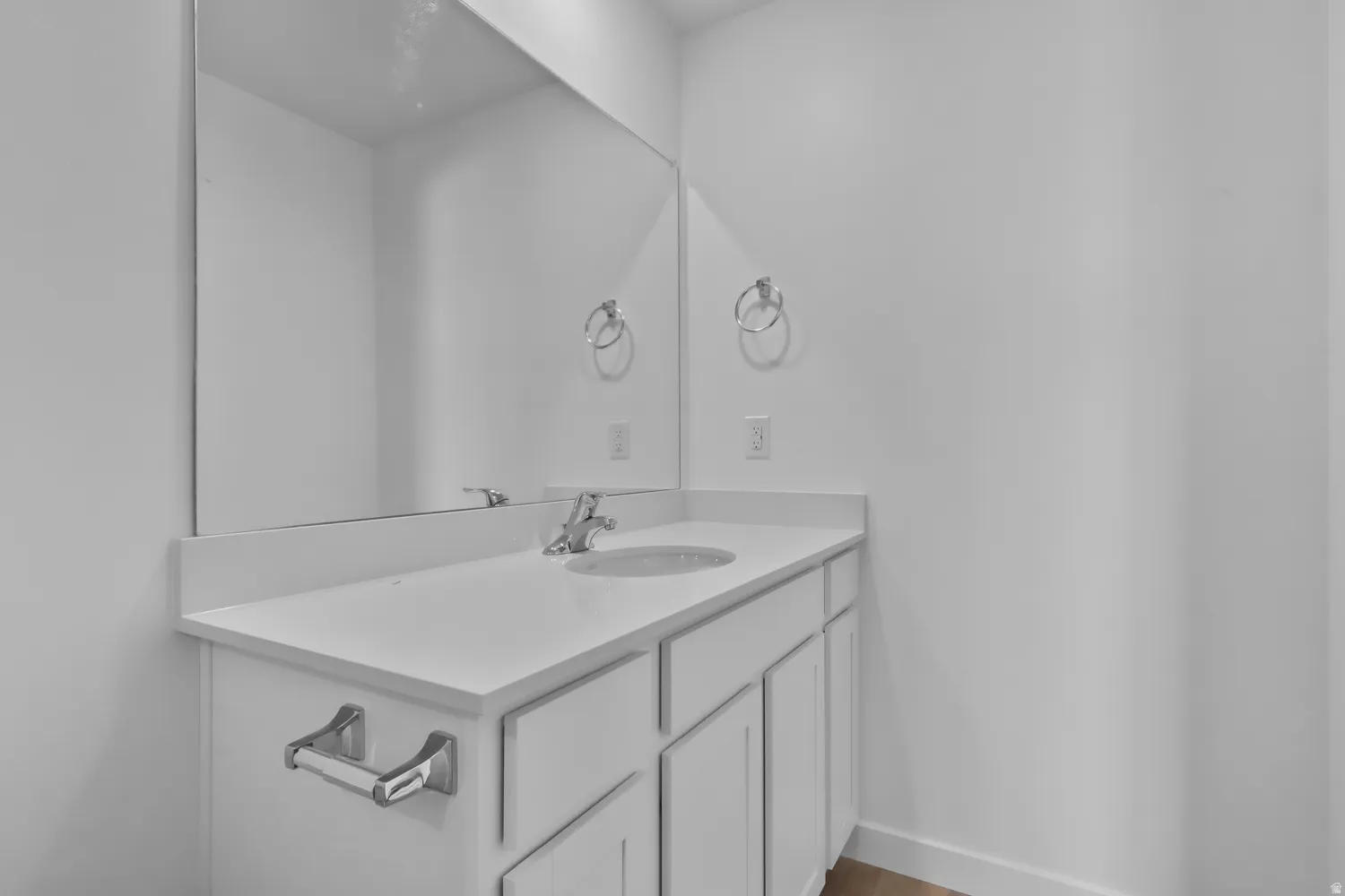 Vanity with an integrated sink and chrome faucet, set against a large wall-mounted mirror