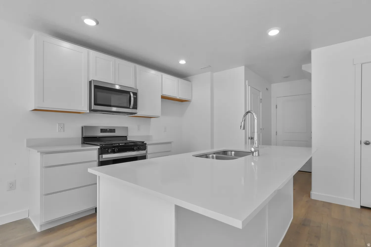 Modern kitchen featuring a white island with an undermount double sink and chrome faucet