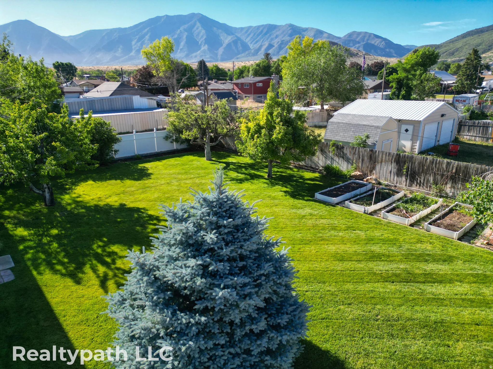 Expansive green lawn with mature trees and raised garden beds