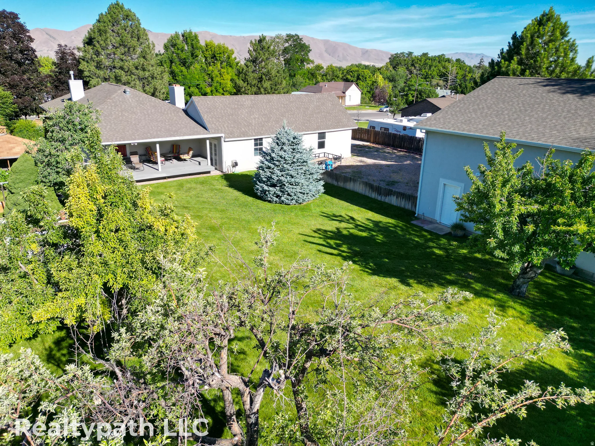 Spacious backyard featuring a manicured lawn, established trees, and a covered porch