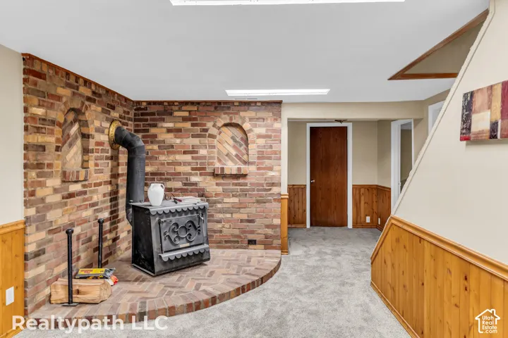 Brick accent wall featuring a wood-burning stove on a brick hearth