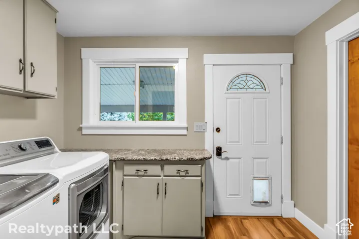Laundry area featuring wood-finish flooring and a white paneled door with a decorative glass transom