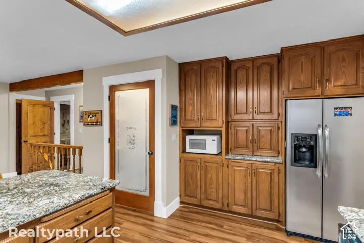 Kitchen featuring wood cabinetry, stainless steel refrigerator, and wood-finish flooring