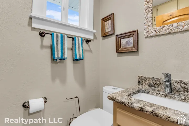Bathroom vanity featuring a polished chrome faucet, under-mount sink, and a granite-finish countertop