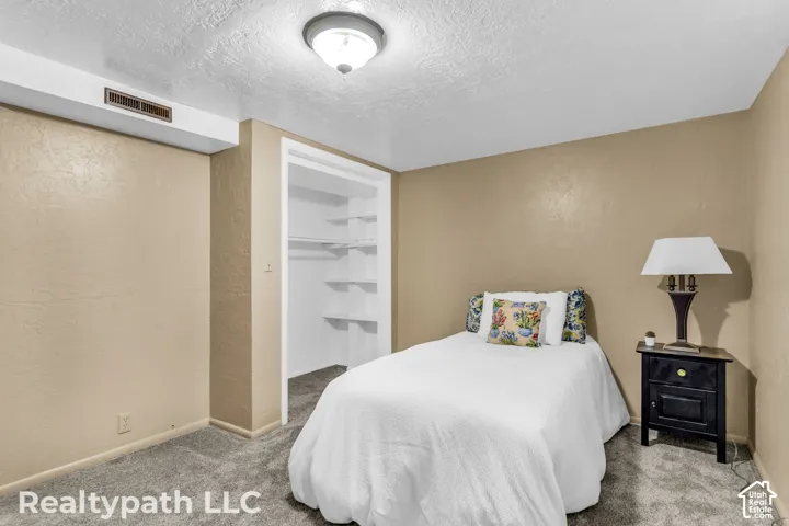 Bedroom featuring neutral-toned walls, textured carpet flooring, and a flush-mount ceiling light fixture
