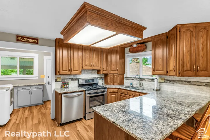 Kitchen featuring wood-finish cabinetry, light-toned granite countertops, and a white subway tile backsplash