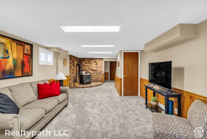 Spacious living area featuring light gray carpet, brick accent wall with fireplace, wood paneling, and recessed lighting