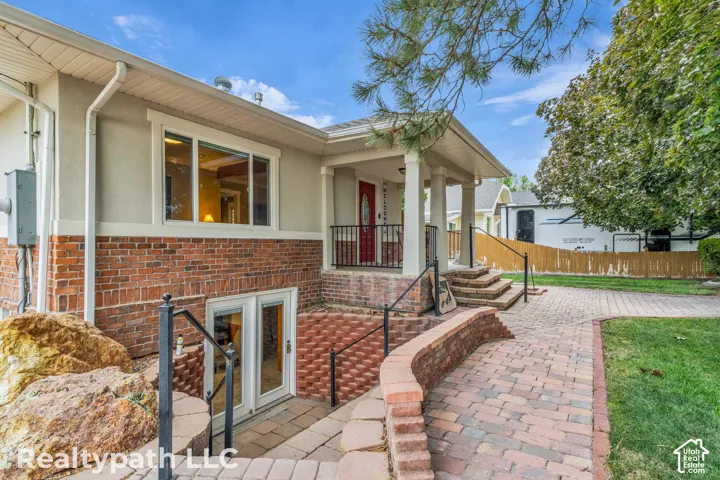 Brick and stucco exterior featuring a covered front porch with white columns and a red entry door
