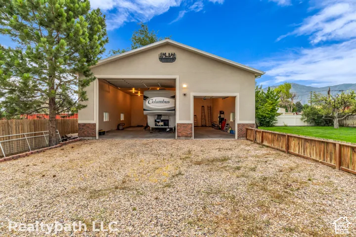 Gravel driveway leading to a two-bay detached garage with stucco and brick facade