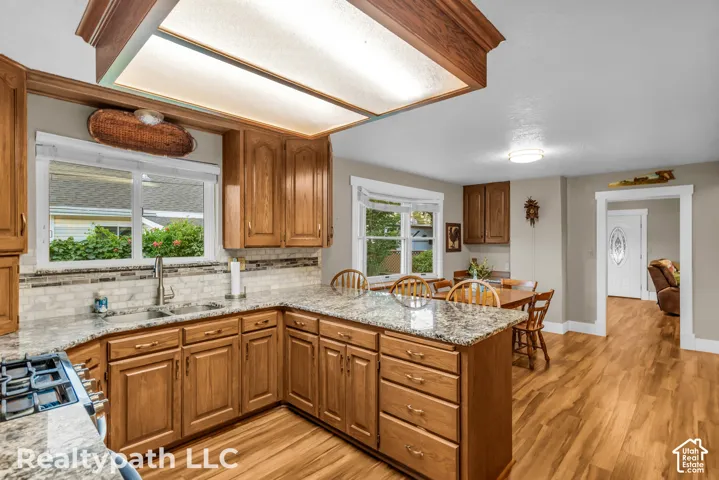 Kitchen featuring wood cabinetry, granite-style countertops, mosaic tile backsplash, and wood-finish flooring