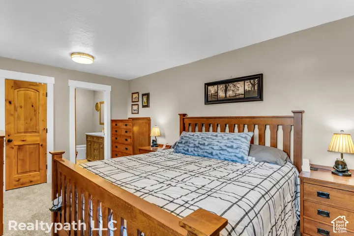 Carpeted room with light neutral wall paint and white trim, featuring a natural wood-finish door with a curved top panel