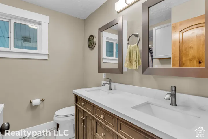 Dual vanity featuring integral sinks, white countertops, dark wood-finish cabinetry, and framed mirrors with overhead lighting