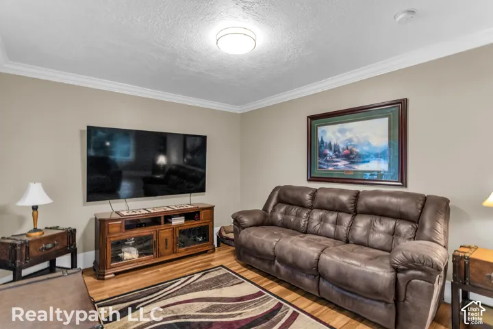 Warm living area featuring wood-finish flooring and crown molding