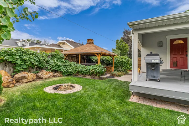 Expansive backyard featuring a central fire pit, mature green lawn, and decorative boulders