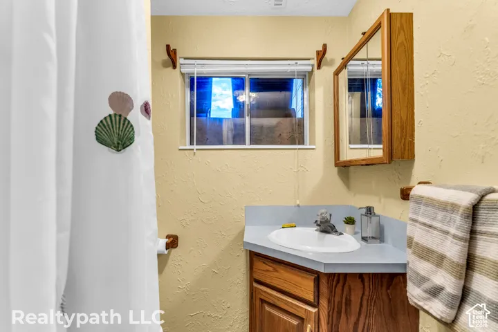 Bathroom featuring a built-in wood-finish vanity with a single basin sink and blue countertop