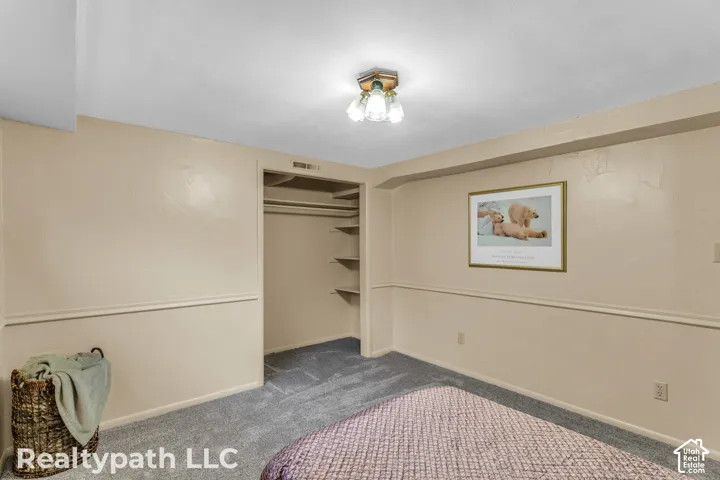 Bedroom featuring neutral-toned walls with chair rail molding, grey carpet flooring, and a built-in closet with shelving and hanging rods
