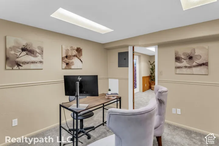 Carpeted room featuring a drop ceiling with recessed lighting, chair rail molding, and a doorway opening to another carpeted area