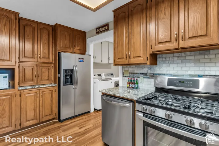 Kitchen featuring wood cabinetry, stainless steel appliances, granite-style countertops, and a subway tile backsplash