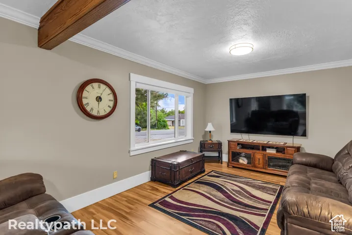 Living space featuring wood-finish flooring, a white trim window, and a ceiling-mounted light fixture
