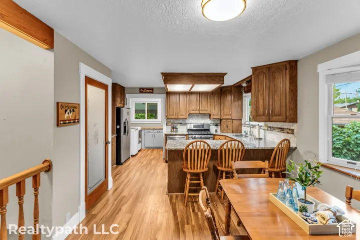 Open-concept kitchen and dining area featuring wood-finish flooring, granite countertops, a tiled backsplash, and recessed and flush-mount lighting