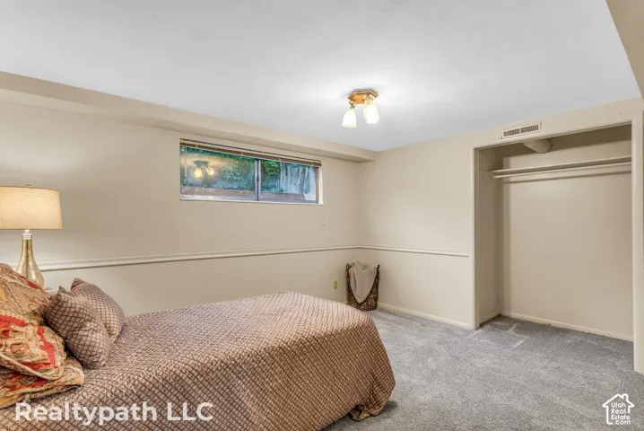 Carpeted room featuring a double-hung window, a built-in closet with hanging rods, a ceiling-mounted light fixture, and neutral wall tones with chair rail molding