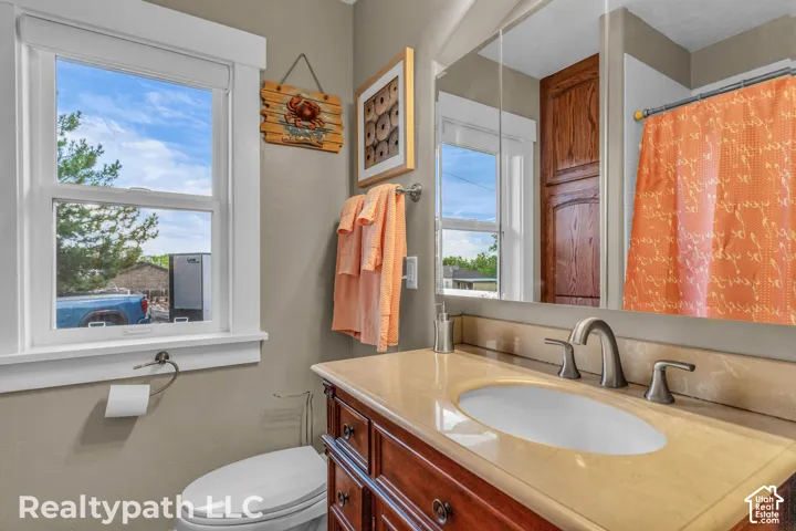 Bathroom featuring a single-pane window, vanity with an integrated sink, polished countertop, and a built-in storage cabinet