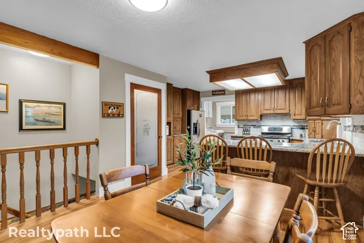Kitchen featuring natural wood cabinetry, stainless steel appliances, granite countertops, and a tiled backsplash