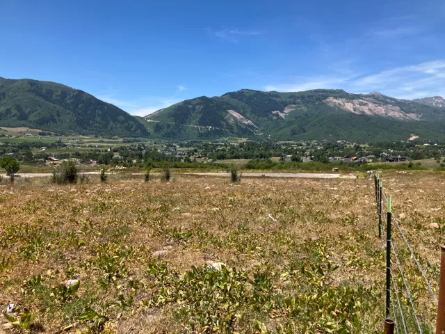 Expansive undeveloped land featuring a partial wire fence and distant mountainous terrain