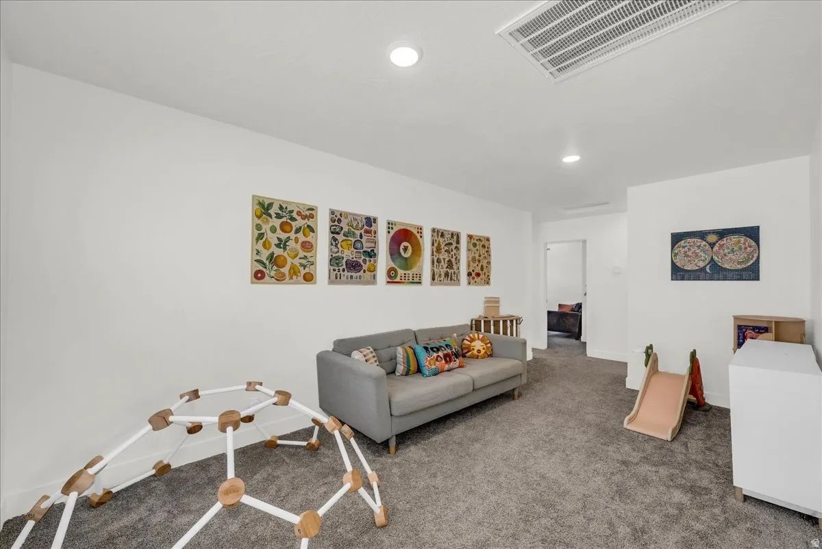 Spacious carpeted room featuring recessed lighting, a white painted ceiling, and a doorway leading to an additional interior space