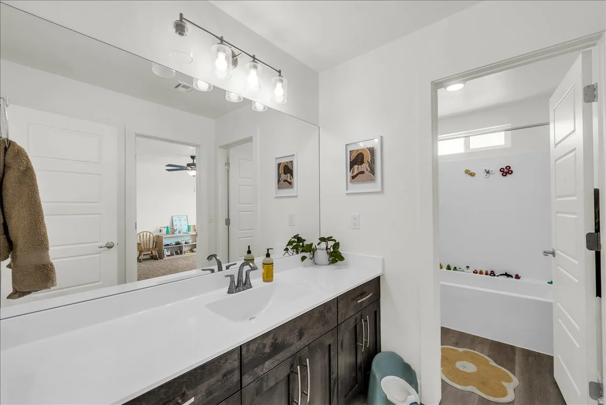 Bathroom vanity featuring a single basin sink, white countertop, and dark wood-finish cabinetry